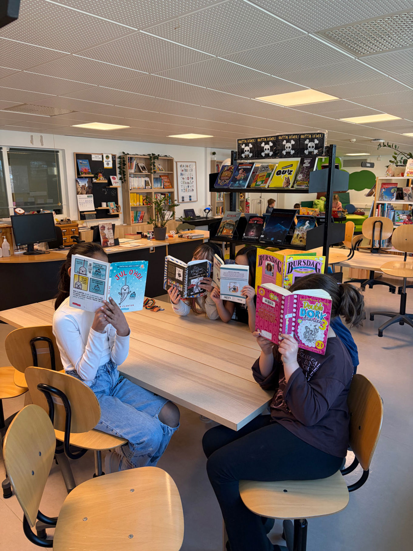 En gruppe mennesker som sitter ved pulter og leser bøker