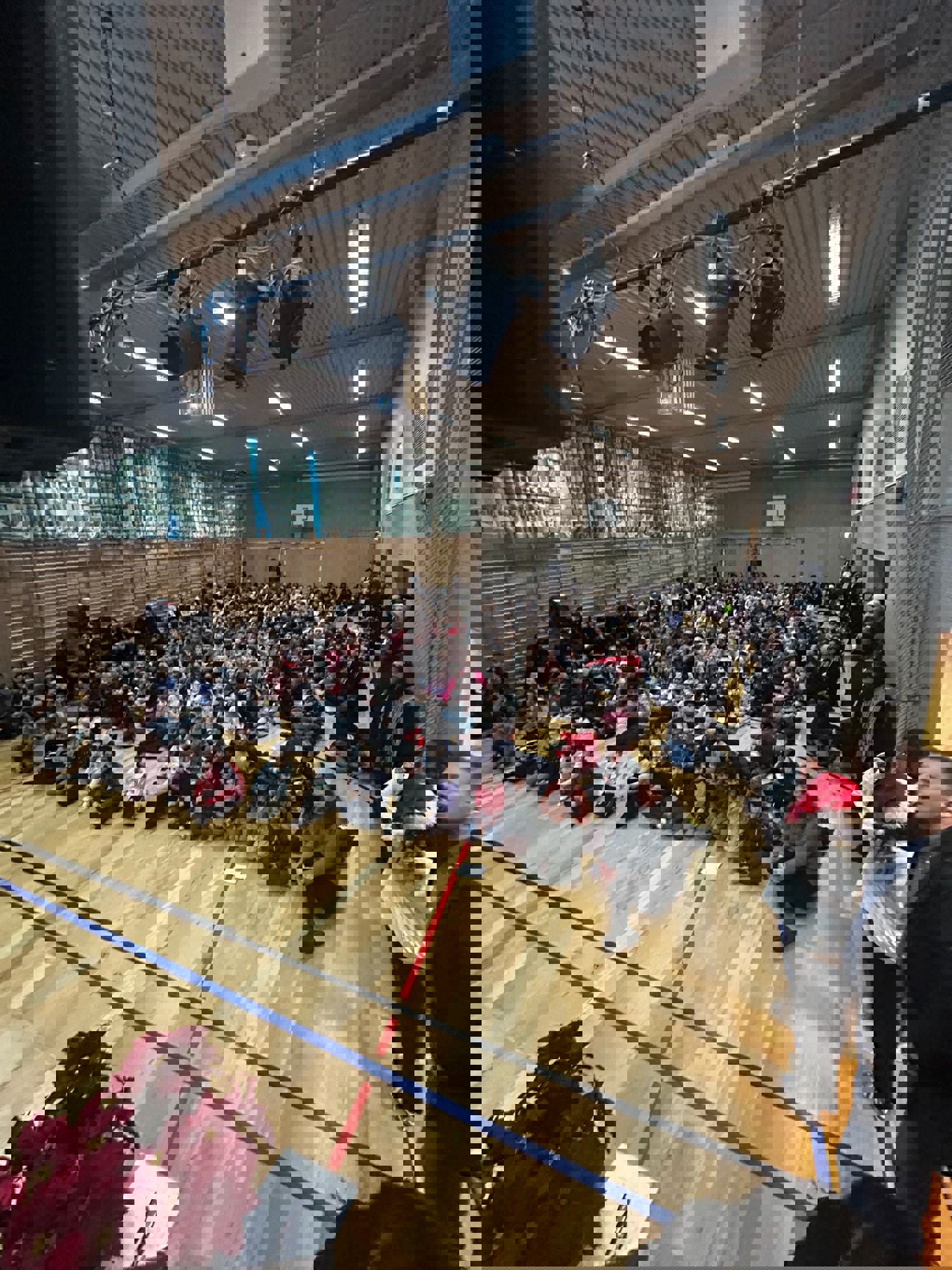 en gruppe mennesker som sitter i et rom med en scene og en stor folkemengde