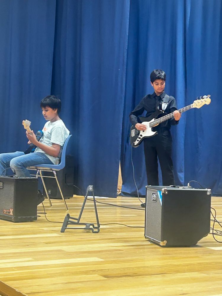 en person som spiller gitar ved siden av en person som sitter på en stol